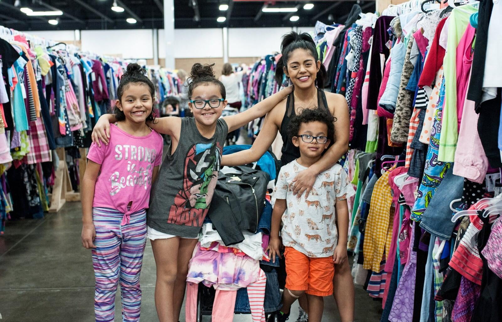 A mom and grandmother stand beside a rack of clothing at a JBF sale in Texas.